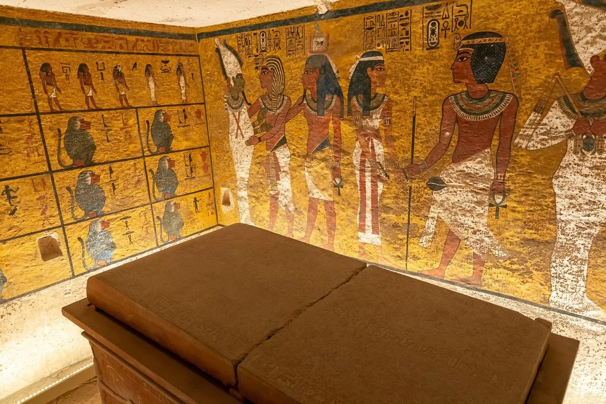 The burial chamber of Tutankhamun's tomb in the Valley of the Kings, with painted walls of gods and the pharaoh behind the stone sarcophagus